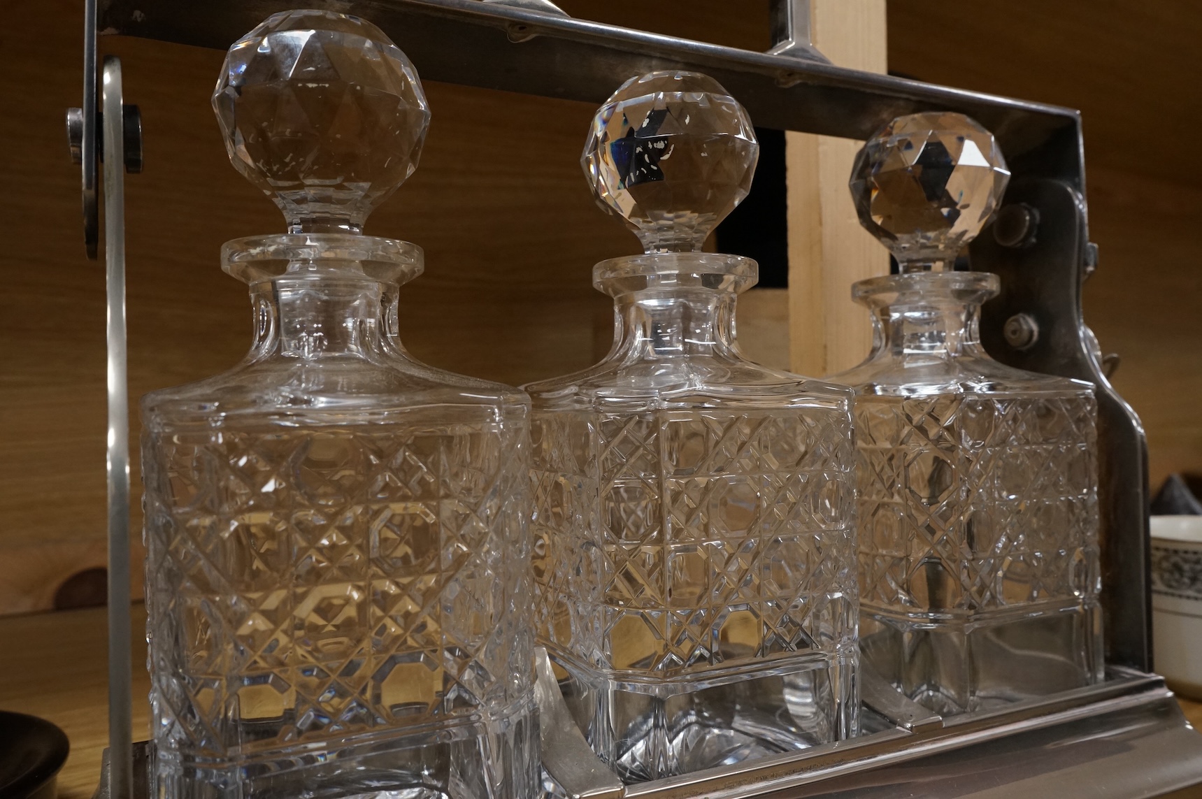 A silver plated three bottle tantalus, 34cm wide.